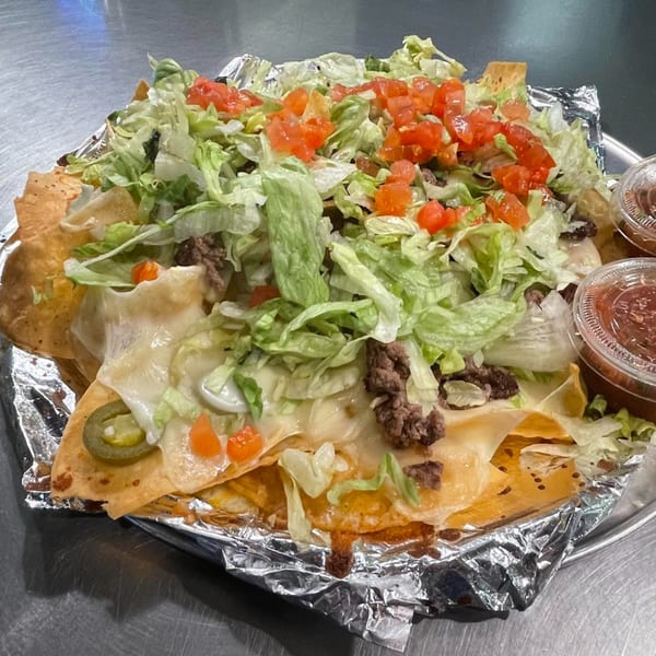 Loaded nachos from Sam's Burger Deli, topped with ground beef, melted cheese, lettuce, and diced tomatoes.