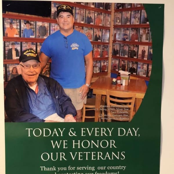 Two men, one a World War veteran, stand in Sam's Burger Deli, honoring veterans.